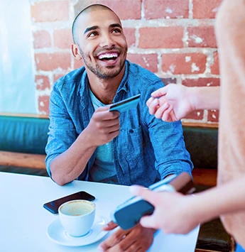 Happy man buying coffee with debit card