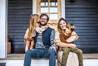 Family of four sitting on the porch of their home